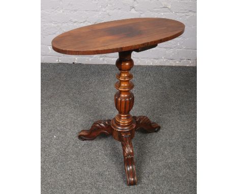 A Victorian rosewood and carved mahogany tripod wine table with oval top.  Cracks and repair to support.