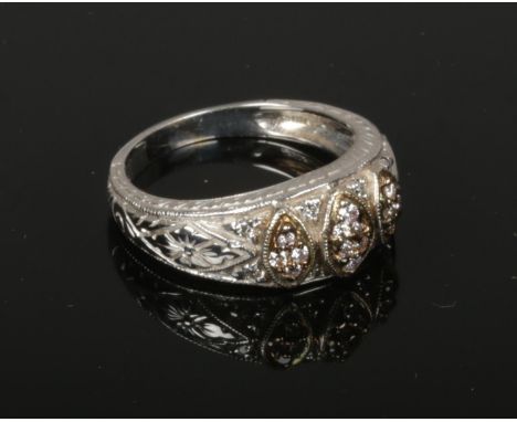 A 14ct white gold and diamond ring. Set with diamonds in three navette shaped panels and with chased shank. 5 grams gross, si