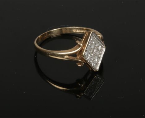 A 9ct gold diamond cluster ring. Set upon a diamond shaped panel between splits shoulders. 2.6 grams gross, size P 1/2.  