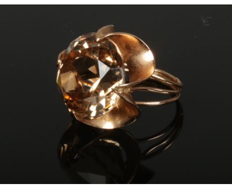 A 14ct rose gold cocktail ring. With a large coloured paste stone in a floriform setting. Stamped .585 outside of the shank. 