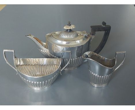 An Edwardian Mappin &amp; Webb three piece silver bachelor's tea service, of oval half-fluted form - Sheffield 1903, the teap