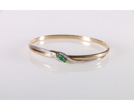 14ct gold bangle set with three Columbian emeralds and diamond chips, clasp stamped '585', 6.8g gross.   The bangle appears w