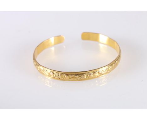 Yellow gold coloured yellow metal West Indian bayras bangle with floral pattern, unhallmaked, 20.7g gross.  The bangle has no