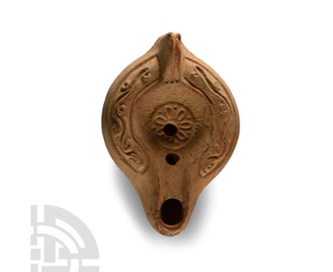 5th century A.D.. Grooved lug handle to rear, discus with two filling holes and a central rosette motif, foliate border to th