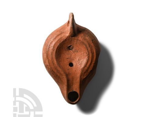 Circa 4th-5th century A.D.. Squat lamp with broad body, shallow discus with raised ribbing, stub nozzle, flange handle to rea