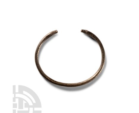 Circa 9th-11th century A.D.. Penannular, round in section with punched scale detailing to the shank, opposed snake-head finia