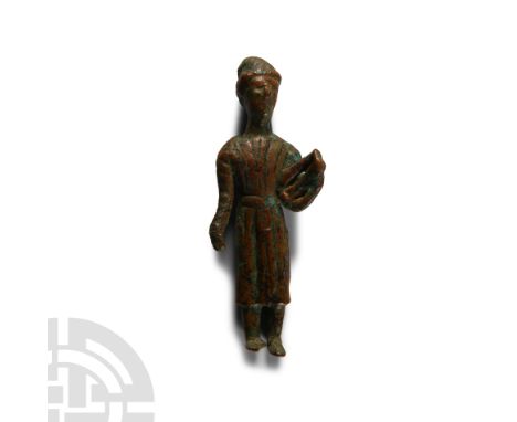 Circa 2nd century A.D.. Standing wearing a three-quarter-length striped tunic belted at the waist and a tight-fitting cap, ly