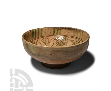 Circa 12th-15th century A.D.. Broad with basal disc, cream-glazed inner face with green detailing, sgraffito design of tulip 