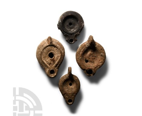 1st-3rd century A.D.. Comprising four mould made lamps, one with ring handle with two shallow grooves on upper part, central 