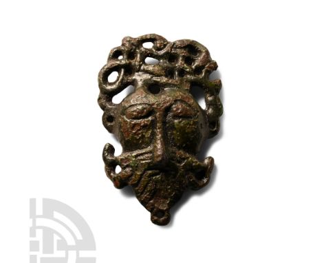 11th century A.D.. A bowed anthropomorphic mount in the form of the face of Odin, with oval right and damaged left eye, beard