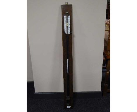 A lacquered metal ship's barometer on oak panel