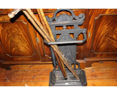 Cast Iron stick stand and assorted walking sticks.