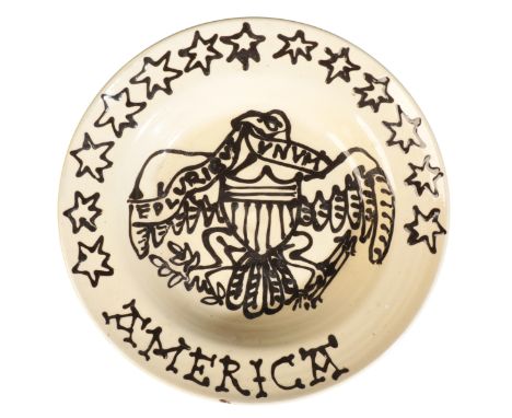 MANNER OF WETHERIGGS POTTERY: AN ENGLISH TERRACOTTA SLIPWARE CHARGER, decorated with an eagle holding a banner 'E Pluribus Un