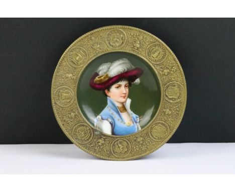 A continental porcelain dish hand painted with a female portrait, set within a brass circular mount.