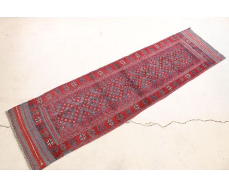 Meshwani runner rug having a red ground with blue geometric detailing. Measures 229 x 60cm.