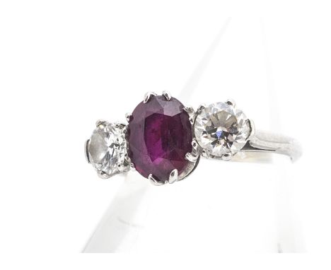A three stone ruby and diamond ring, the oval mixed cut ruby in claw setting flanked by brilliant cut diamonds all set in whi