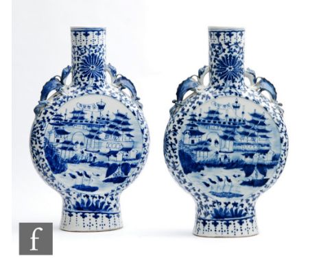 A pair of 19th Century Chinese blue and white moonflasks in the Kangxi style, each rising from a high oval footring, the cent