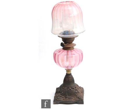 A late 19th Century oil lamp with a cast iron base relief moulded and pierced with flowers and foliage and a scene of a boati