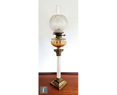 An early 20th Century Corinthian column form oil lamp, the stepped brass base rising to a hobnail cut crystal column and a di