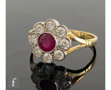 An 18ct hallmarked ruby and diamond daisy cluster ring, central collar set ruby to a brilliant cut eight stone diamond surrou