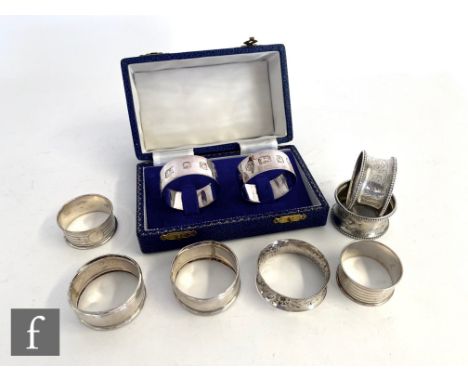 A cased pair of modern hallmarked silver circular napkin rings, London 1977, with four earlier pairs to include foliate engra