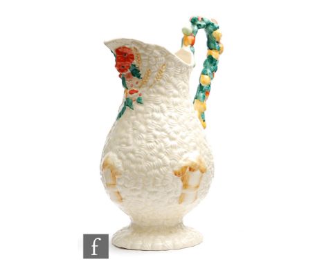A Clarice Cliff Celtic Harvest pattern jug of footed baluster form, relief moulded with corn, fruit and foliage picked out in