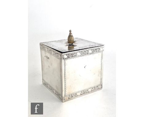 A hallmarked silver square sectioned tea caddy of plain form with bright cut engraved foliate borders and stylised pineapple 