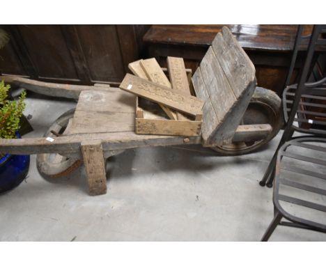 A vintage wooden garden barrow and selection of carved panels