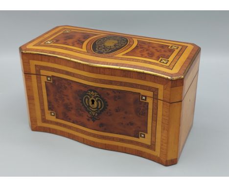A satinwood and burr walnut serpentine fronted tea caddy, with brass inlaid decoration, 23cms wide 