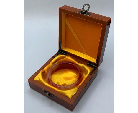 A variegated carnelian bangle in a wooden presentation box. Weight: 72g, internal diameter: 6cm. 