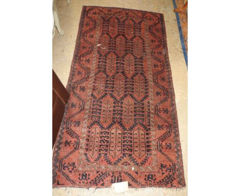 An antique belouch rug, the all over geometric design on ruby ground, within corresponding border 194cm x 100cm
