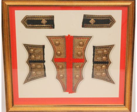A framed display group of parts of a Coldstream Guards uniform depicting buttoned and braided sleeve and shoulder epaulettes,