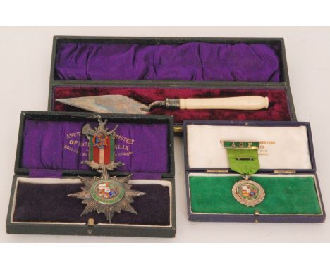 Two Ancient Order Of The Foresters enamelled jewels together with a small plated and ivory handled foundation stone trowel in