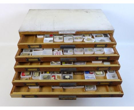 A collection of watch parts, contained within an oak ten drawer table top chest, labelled 'A Beechpac Fitnest', comprising a 