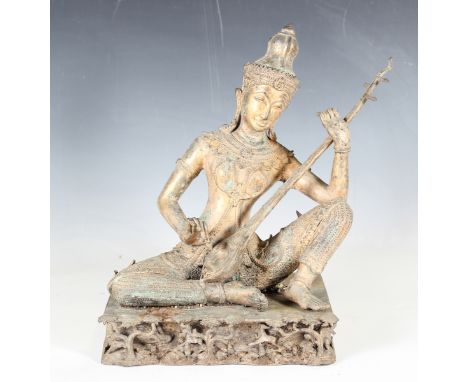 A late 20th century gilt and green patinated bronze figure of a Thai musician, seated on a rectangular naturalistic plinth, h