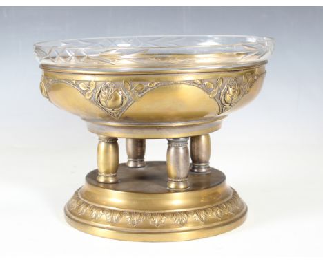 An early 20th century pressed brass centrepiece bowl, probably WMF, fitted with a circular glass liner, height 22cm, diameter