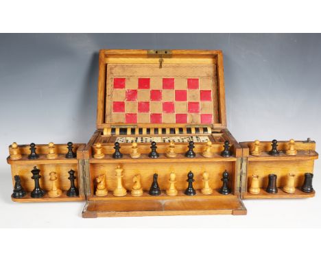 An Edwardian oak cased games compendium, the interior fitted with a chess set, height of king 6.5cm, draughts, dominoes and p