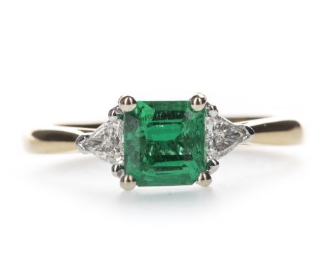 EMERALD AND DIAMOND RING, the emerald of approximately 0.76 carats, flanked by two trillion cut diamonds totalling appoximate