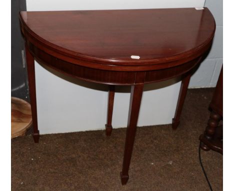 A Georgian style mahogany demi-lune fold over card table, on tapered legs and spade feet