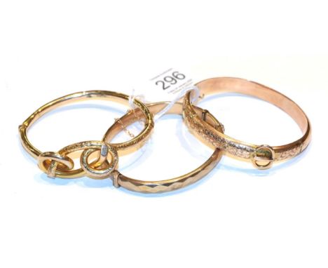 A foliate and buckle motif hinged bangle, stamped '9' and '.375'; a 9 carat gold hinged bangle; and another example with indi