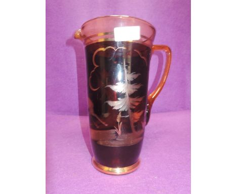 A glass jug or pitcher with ruby glass and cut deer and forest design