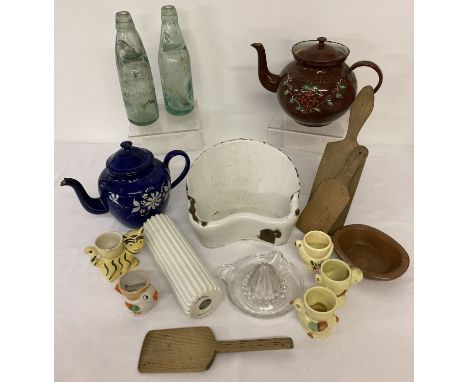 A box of assorted vintage kitchenalia. To include: enamel teapots, glass bottles, wooden butter pats, novelty egg cups and ce