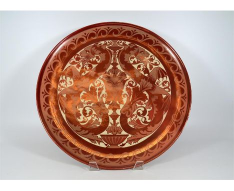 A Maw & Co ruby lustre charger, decorated with dragons and a central mask. Circa 1890. Diameter 45.5cm.