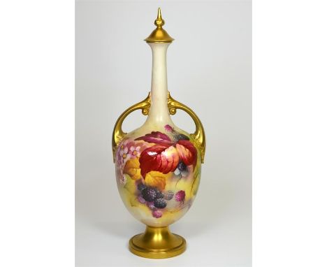 A Royal Worcester twin handled vase, with fruit decoration, gilded handles and surmounted by finial top, signed K. Blake. Sha