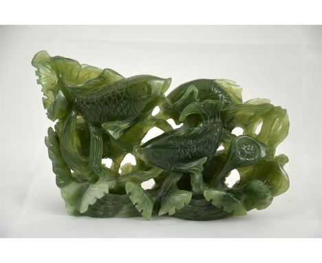 A Chinese carving of a shoal of fish, green stone possibly jade. Height 14cm.