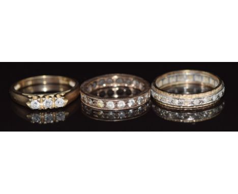 Two 9ct gold eternity rings and a 9ct gold ring set with three diamonds, 7.5g, size O, K &amp; N&nbsp;