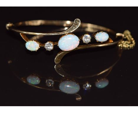 A c1900 18ct gold bangle set with three oval opal cabochons and two old cut diamonds, each approximately 0.35ct, 14g