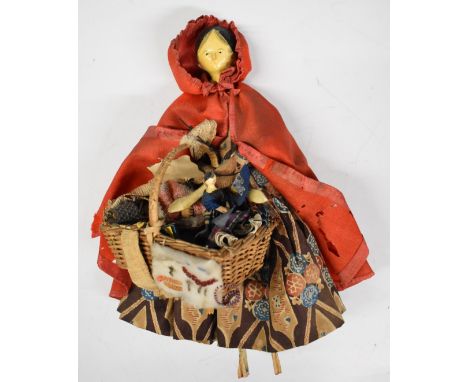 19thC Grodnertal painted wooden Eastern pedlar doll wearing a red cloak and a basket with her wares including a miniature Gro