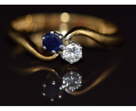 An 18ct gold ring set with a diamond and sapphire in a twist setting, 2.7g, size M