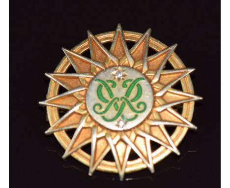 A 9ct gold brooch set with green enamel initials and diamonds inside a sunburst design, by Garrard &amp; Co, 6.2g 2.6cm
